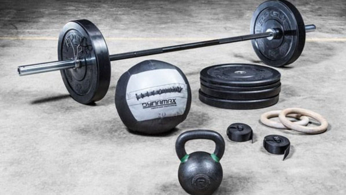Barbell, bumper plates, kettlebell, medicine ball, and gymnastic rings arranged for Crossfit workout