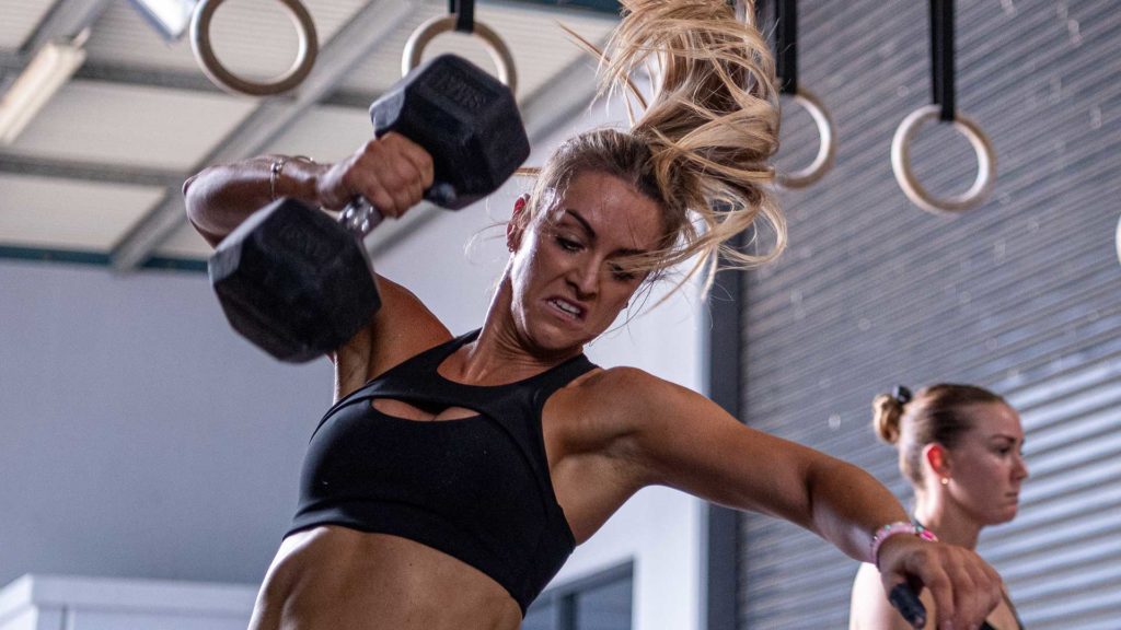 Athlete performing a dumbbell snatch during the 24.1 CrossFit workout